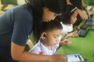 Woman teaching young boy to use a tablet
