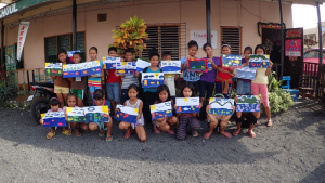 Two rows of children holding up art work at a rural community