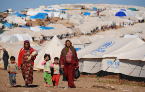 2 ladies and their children can be seen walking within the refugee camp