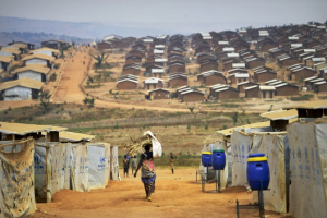 A women can be seen carrying a bag, walking along the pathway in the refugee camp