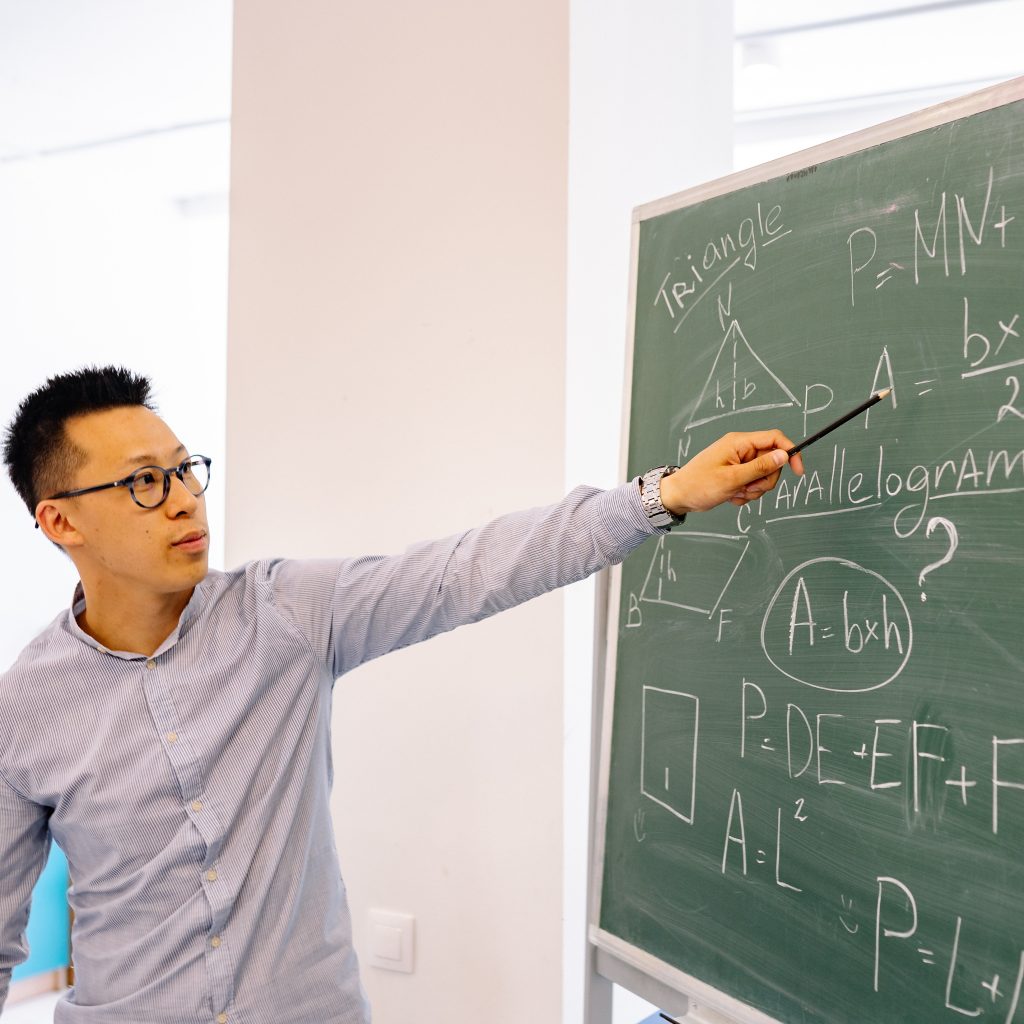 asian male teacher pointing to chalkboard worried about mental health